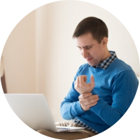 Image of man holding his wrist and checking insurance on his computer